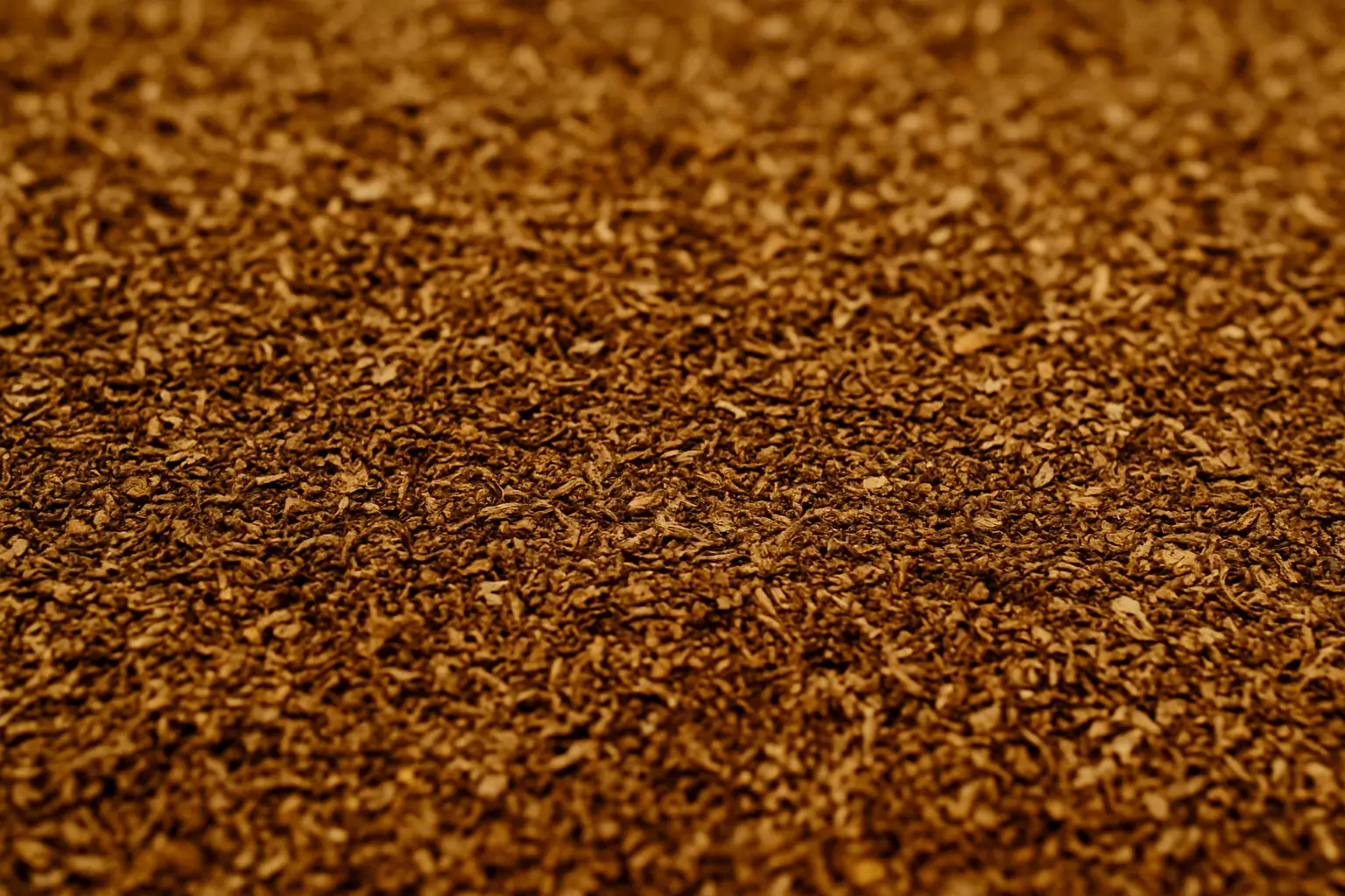 Vente de bois paillage 1 Gros plan d'une surface texturée recouverte de petites feuilles de thé brunes séchées ou de matières végétales similaires, créant une apparence dense et uniforme, idéale pour le paillage afin d'améliorer la santé du sol et de conserver l'énergie.